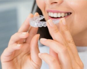 Woman holding a clear aligner as an alternative to metal braces
