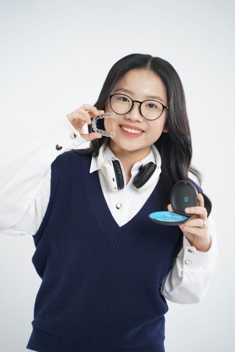 Smiling woman holding clear Invisalign aligners