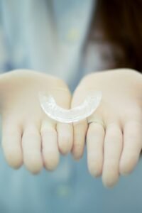 Clear orthodontic retainer held in a hand after braces or Invisalign treatment
