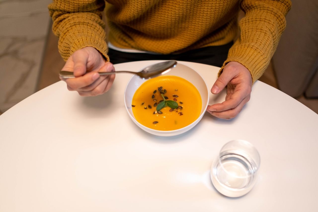 Person eating a bowl of pumpkin soup